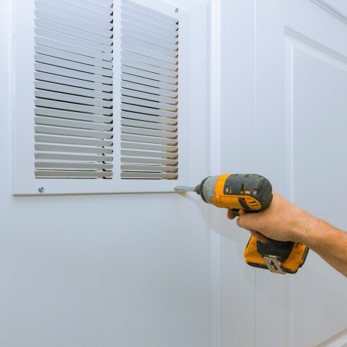 Man is holding hand drill in hands. Worker installing the wall vent restoration process repair works renovation in the flat.